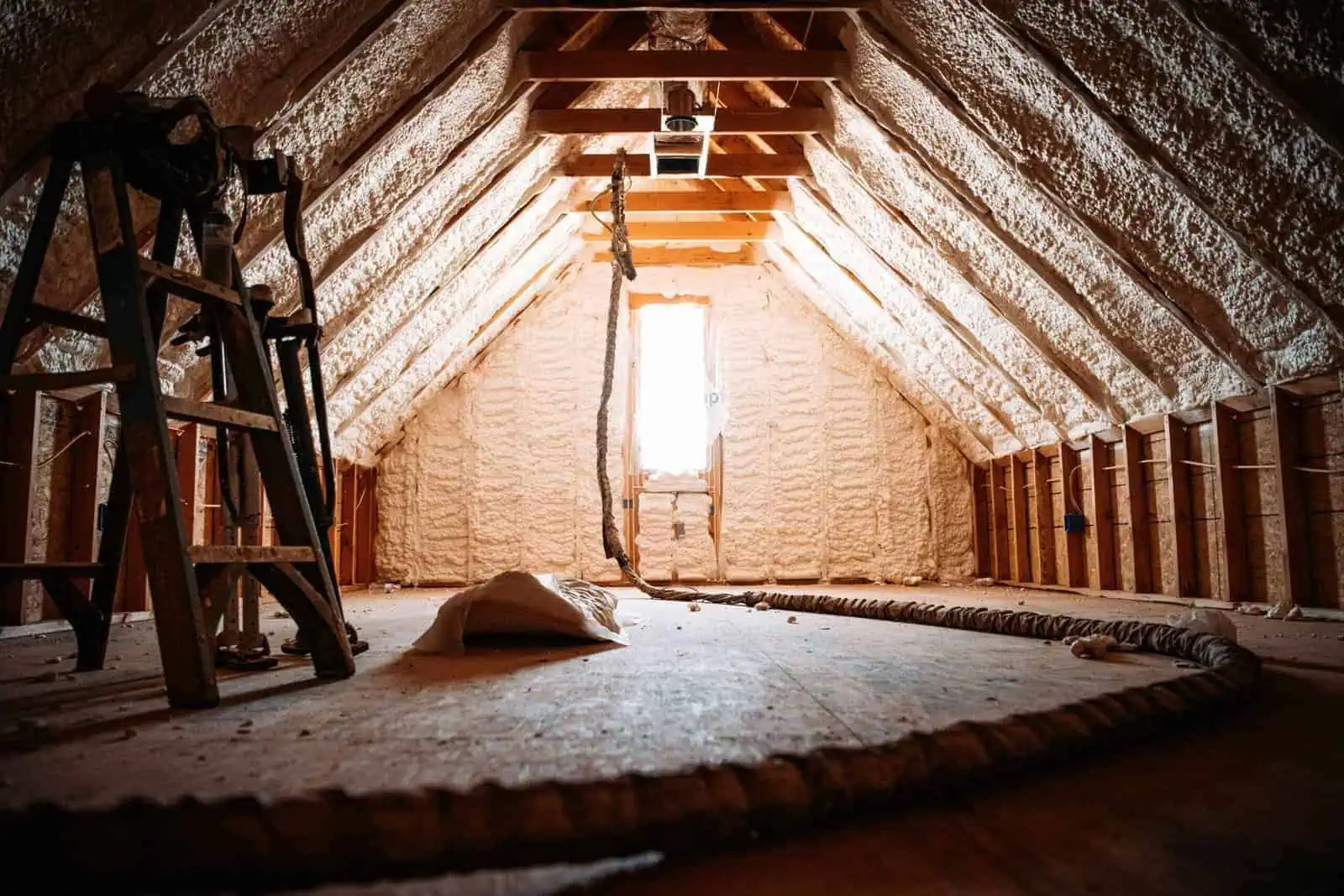 Attic with spray foam insulation and wooden beams in California home.