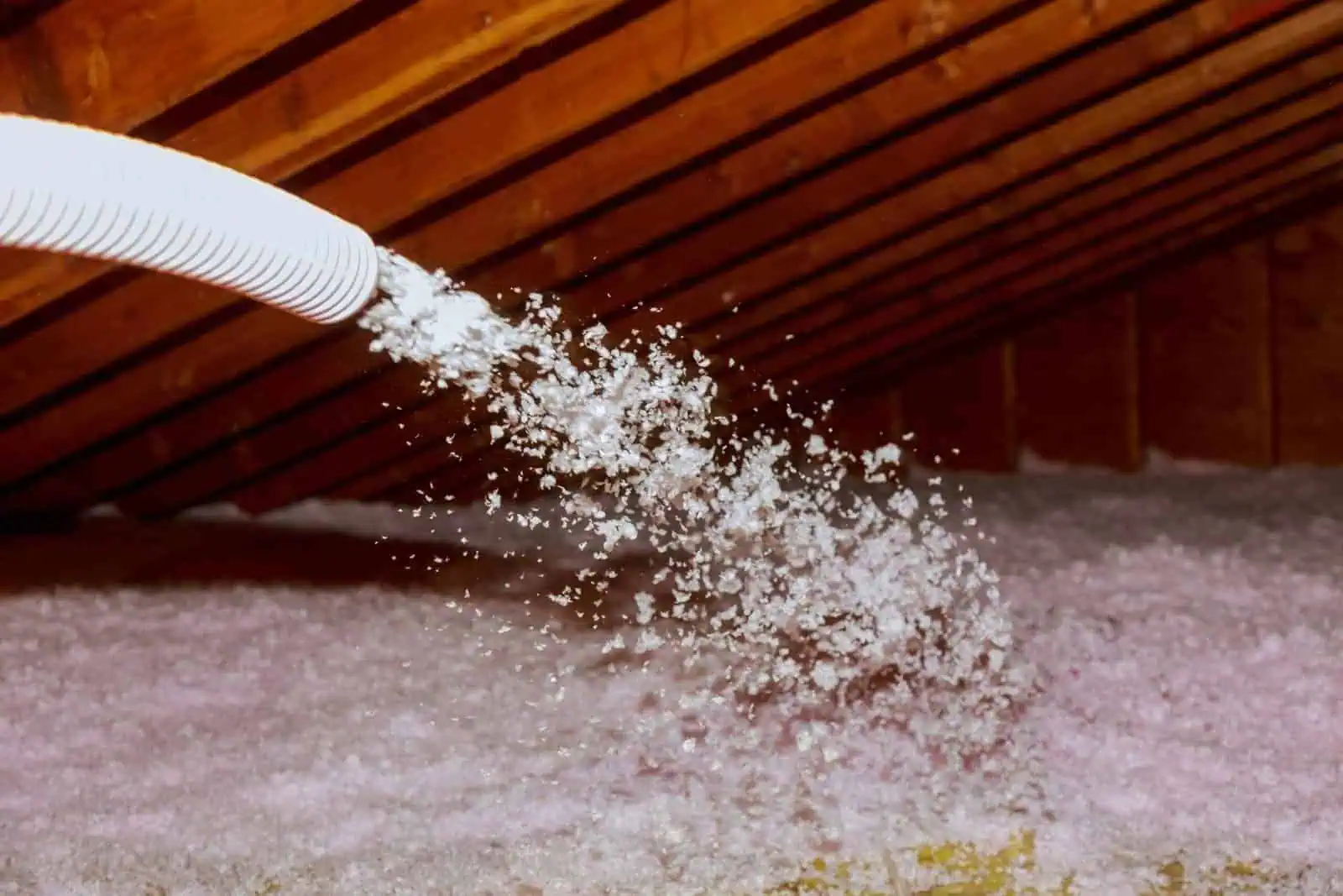 Attic insulation being blown in through a hose in a home.