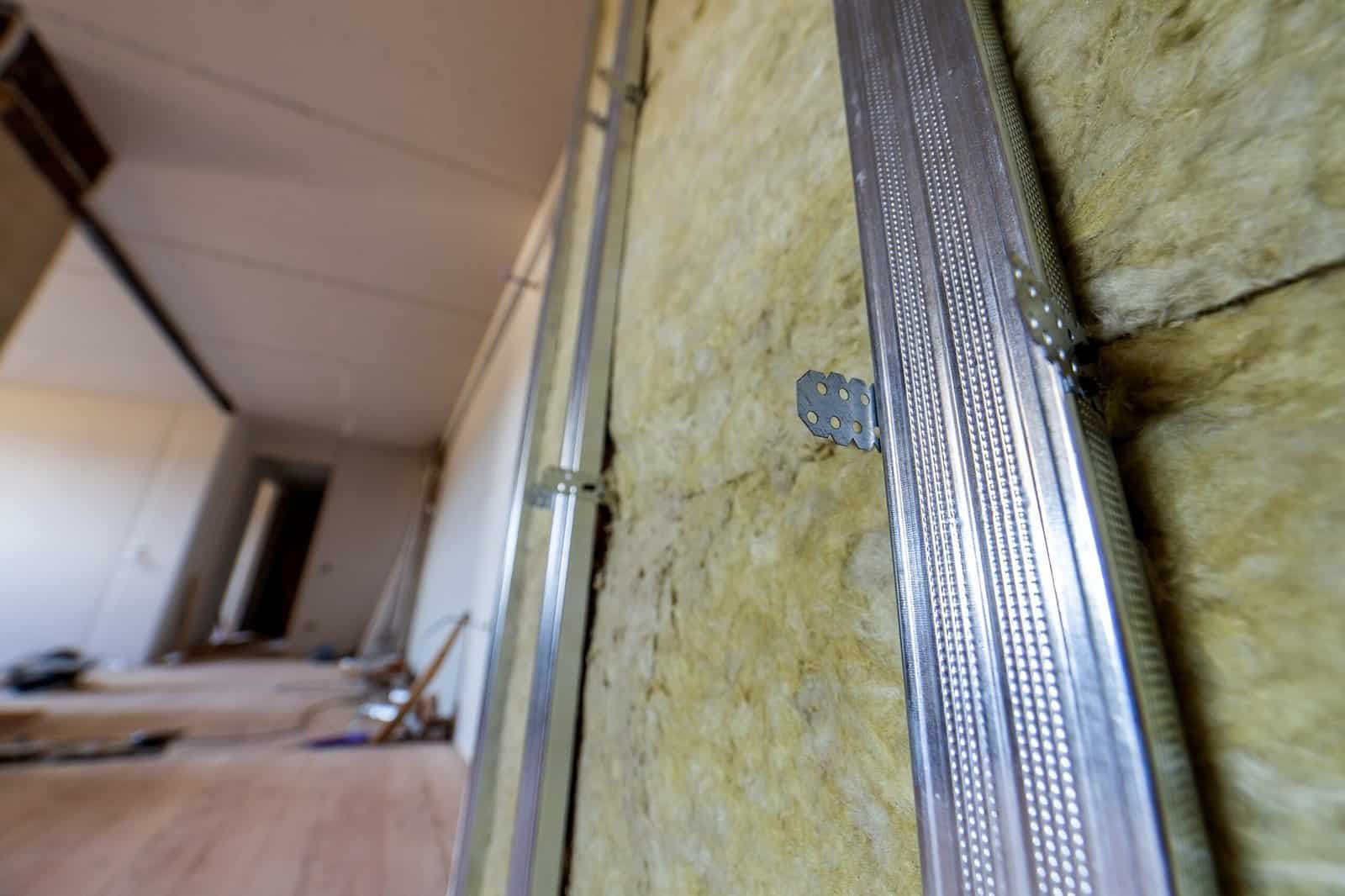 Close-up of metal framing and insulation in a building wall.