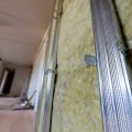 Close-up of metal framing and insulation in a building wall.