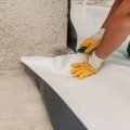 Worker applying insulation to wall for soundproofing and thermal efficiency.